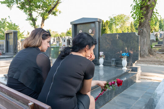 Women visiting grave mourning loss and remembering loved one
