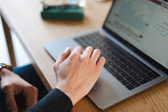 A person's hand is typing on a laptop keyboard, with a chart displayed on the screen.