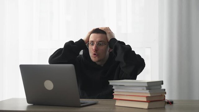 A man stares at his laptop screen in surprise and is stunned.
A shocked man at his desk in an office.