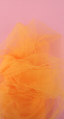 Bright orange tulle fabric on pink background.  Abstract transparent material curve wave.