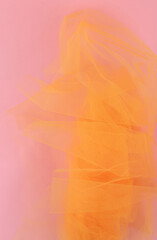 Bright orange tulle fabric on pink background.  Abstract transparent material curve wave.