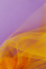 Bright orange tulle fabric on purple background.  Abstract transparent material curve wave.