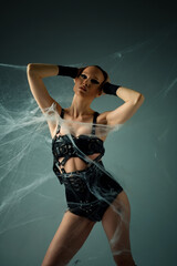 Obraz premium Woman in black leather harness and spiderwebs posing in a dark fantasy concept