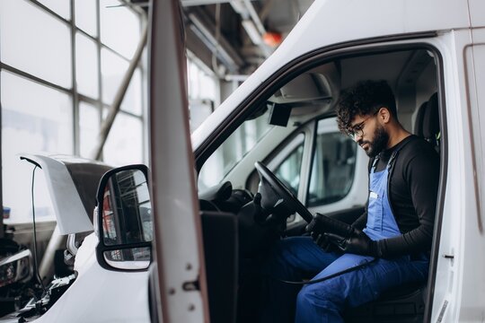 Mechanic diagnosing van engine using diagnostic tool