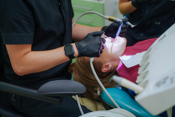 The doctor treats the patient's teeth. Dental treatment. The girl is lying in the dentist's chair. Oral care at the dentist. Dental instruments.
