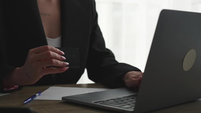 A woman with a credit card and laptop in an office makes a bank payment.
Online credit card payment