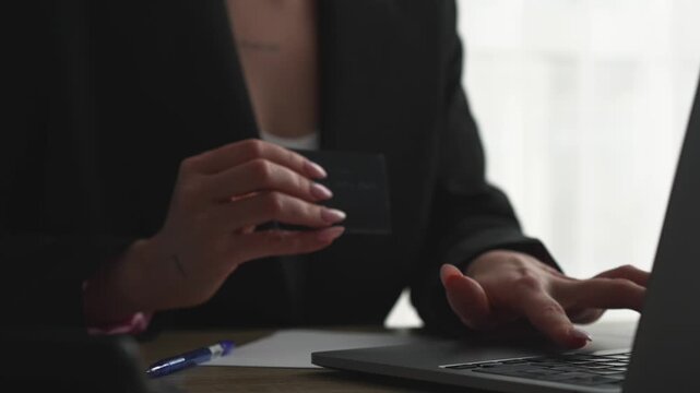 A woman with a credit card and laptop in an office makes a bank payment.
Online credit card payment