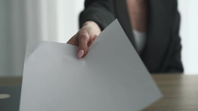 A businesswoman holds out her hand with a white piece of paper for signing.
A girl holds documents in her hands.