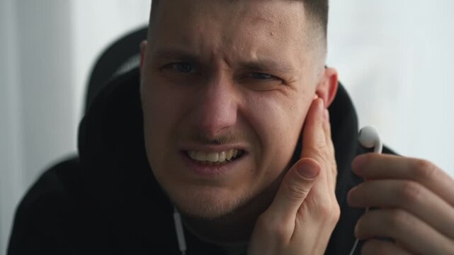 The harm of using headphones.
Ear health.
A person wearing headphones experiences ear pain due to listening to loud music.