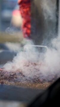 Asada steaming on an outdoor flattop grill with a trompo in the back ground