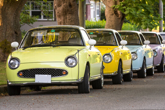 Canada, BC, Vancouver.  Row of identical small passenger cars on treelined street.