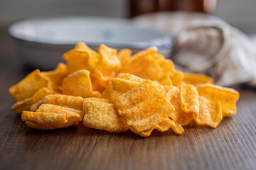 Crispy salted chips on wooden table.