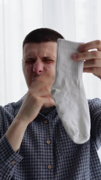 A smelly white sock.
A man inhales the smell of a smelly sock.
Dirty white socks in a guy's hands.