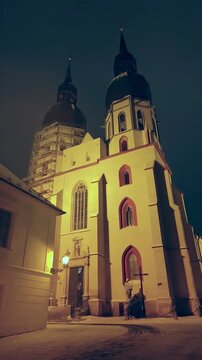Atmospheric vertical HD video of St. Nicholas Basilica in Trnava, Slovakia. Night winter scene with fresh snow and high-quality authentic audio of church bells ringing. Perfect for social media 