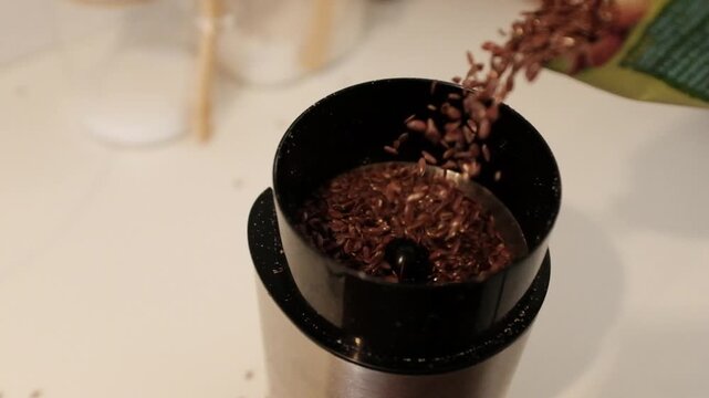 Close-up of flax seeds being ground into a fine powder or meal. This footage highlights healthy superfood preparation, organic nutrition, vegan protein sources, and the texture of raw pumpkin