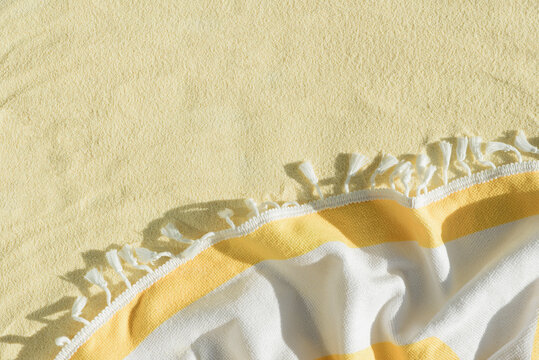 Yellow Beach Towel with Striped Fabric and Tassels. Summer Vacation Flatlay