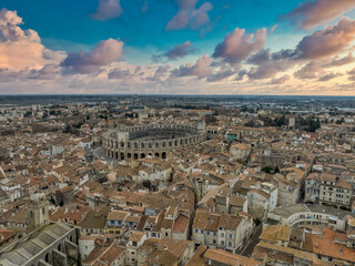 Fototapeta premium A Golden View of History: The Roman Amphitheatre and Terracotta Rooftops of Arles, Provence, Framed by the Rhône River sunset sky