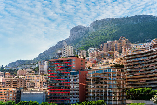 cityscape sunset view of a Monte Carlo city in Monako with high buildings, tall skyscrapers and industrial landscape with evening mountains on background