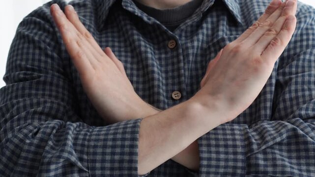 A categorical gesture of refusal with the hands.
A man in a shirt crosses his arms in front of himself, demonstrating his categorical nature.