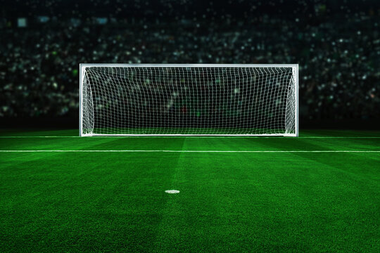 Empty soccer goal on a vibrant green field under bright stadium lights. Dramatic night atmosphere with a blurred crowd background, perfect for sports marketing, competition, and goal-setting concepts.