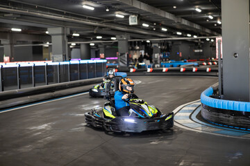 Two go-karts racing on a sleek indoor track in an exhilarating environment filled with excitement.
