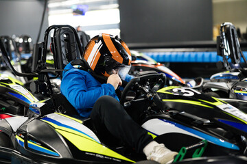 A driver prepares for a go-kart race, showcasing concentration and excitement in the racing environment. © Dejan