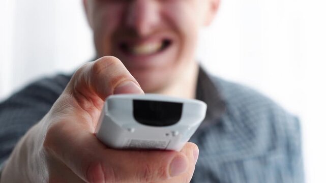 A man holding a faulty TV remote control.
The man is nervous because the remote isn't working.
Technical problems