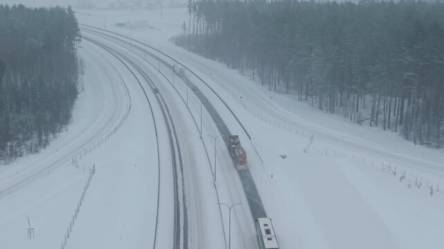 Aerial view of multilane highway with freight truck negotiating snowy bend along protected route