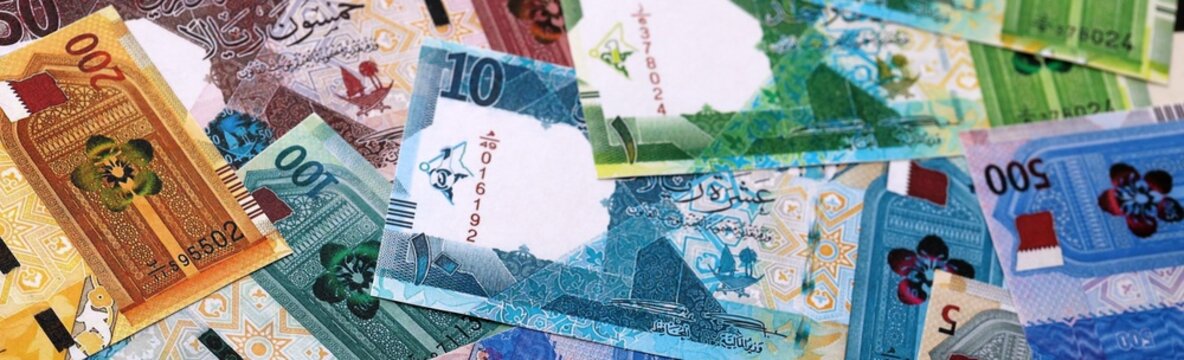Qatari riyal money bills pile on table. Qatar banknotes of QAR currency close up
