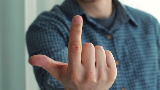 A man gestures with his finger, "Come here."
A man beckons someone to him.
Gestures "Come here."