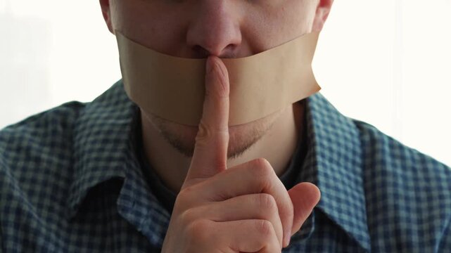 A man with duct tape over his mouth.
A gesture of silence.
Keeping secrets.
Portrait of a man with duct tape over his face.