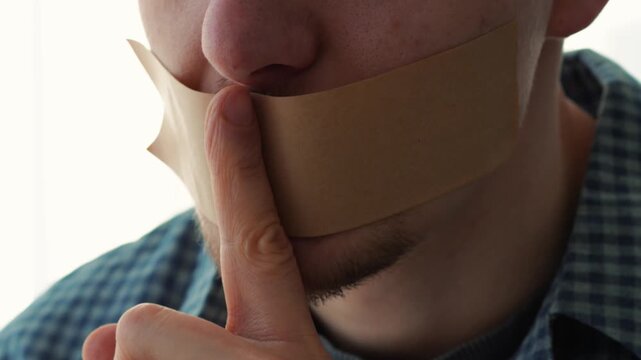 A man makes a silence gesture with his mouth closed.
Silence and secrecy.
Keeping secrets and information