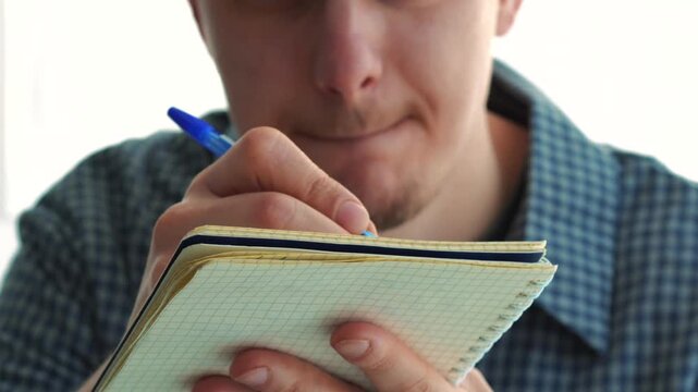 Writing the script with a pen in a notebook.
A screenwriter writes a script on paper.