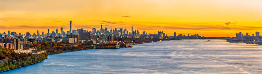 New York and Jersey City skyline panorama as viewed from George Washington Bridge, above Hudson River, at sunset.