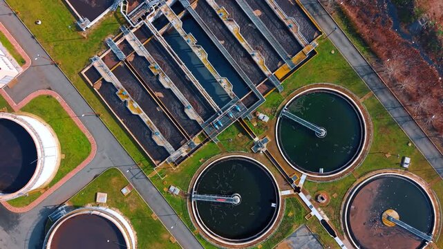 Detailed aerial view of sewage treatment plant infrastructure. Overhead view of multiple circular and rectangular basins for industrial water purification.