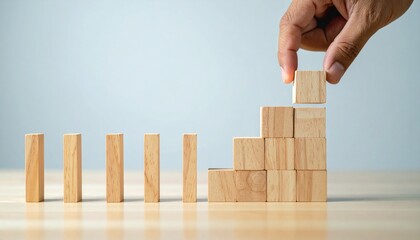 Hand Placing Wooden Block on Ascending Stack Representing Growth and Progress