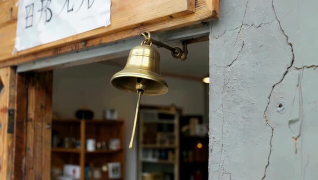 Ultra 4K close up footage of an old fashioned golden bell above shop door gently moving tinkling emphasizing reflections texture vintage charm lifestyle architectural stock 
