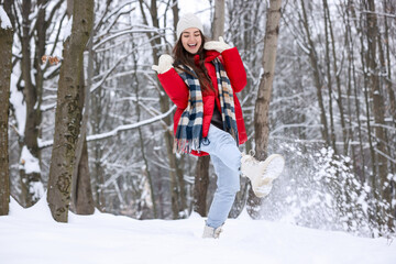 Fototapeta premium Happy woman kicking snow in winter forest