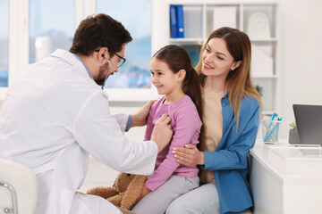 Fototapeta premium Little girl and her mother having appointment with pediatrician in hospital. Doctor checking child with stethoscope