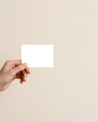 Obraz premium Person Holding Blank White Business Card Mockup Against Minimalist Beige Background with Negative Space