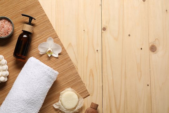 Clean towel, cosmetic products and orchid on wooden table, flat lay. Space for text