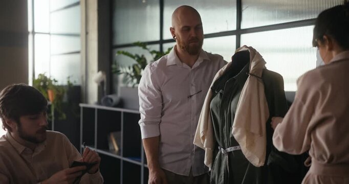 Creative minds engage in fashion design, measuring and discussing a new clothing piece in a stylish studio environment