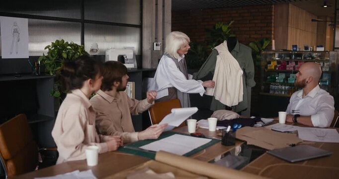 Designers gather in a vibrant studio to discuss and showcase creative clothing designs and innovative fashion concepts