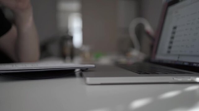 Close-up of hand taking handwritten notes beside laptop at home office desk. Concept of productivity, planning and focused remote work.