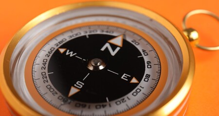 Fototapeta premium One compass on orange background, closeup view