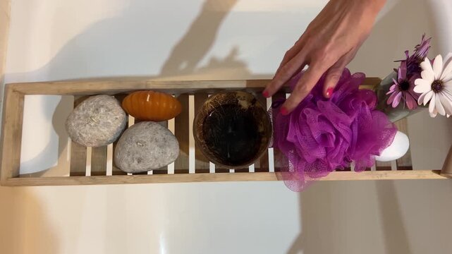Flat lay de mano colocando set de ba&ntilde;o ordenado en bandeja de ba&ntilde;era