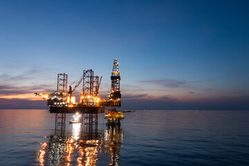 Fototapeta premium Aerial view of offshore jack up rig in a shipyard during sunset for oil and gas exploration and production.