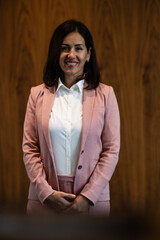 Professional business woman smiling standing against wood paneling