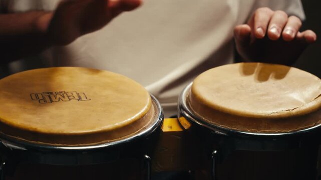Bongo drummer percussionist performing on a stage with conga drums set kit during jazz rock show performance, tumbadora quinto with latin cuban afro-cuban jazz band performing in the background