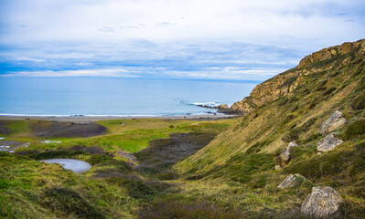 Obraz premium Rocky coastline and sandy beach with cliffs and ocean waves. High quality photo